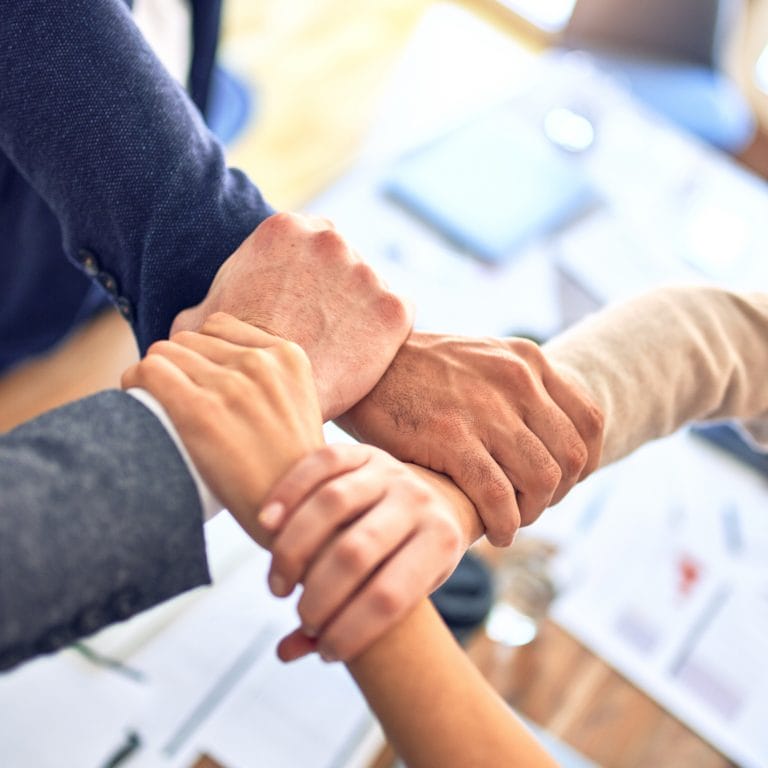 Eine Gruppe von Menschen hält sich die Hände. Symbolisch für ein starkes Netzwerk der maxXse Versicherungsmakler.