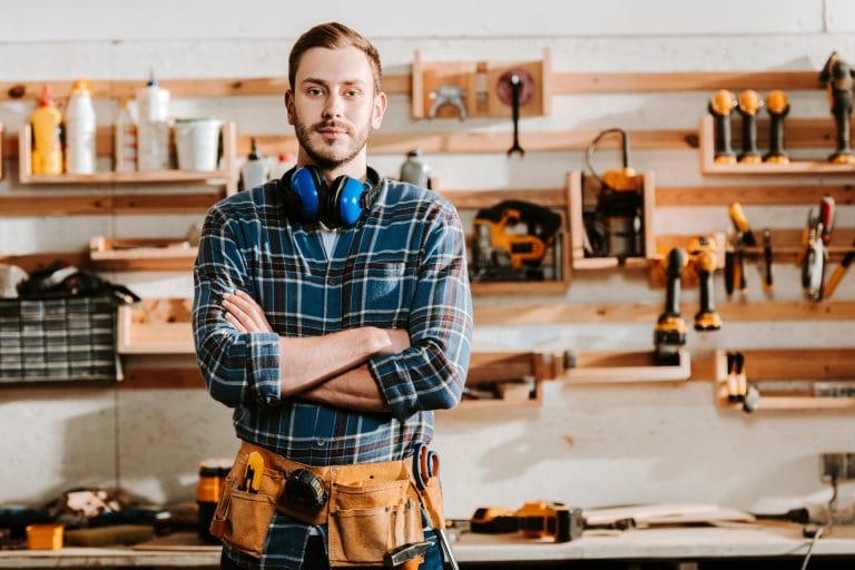 Ein selbstständiger Handwerker steht vor seiner Werkbank. Symbolisiert eine private Krankenversicherung für Selbstständige und Freiberufler.